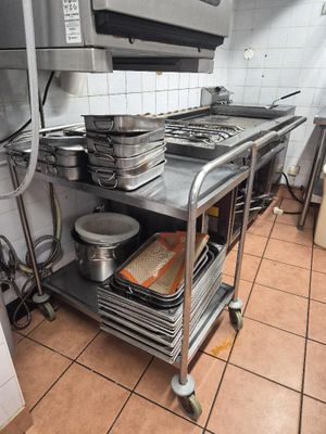 several pans and pans are stacked on a metal cart in a kitchen