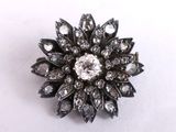 a close up of a diamond flower broochle on a white surface
