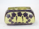 a yellow and black vase with black flowers on it