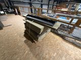 Plusieurs piles de bois sont empilées dans une grande pièce équipée d'un support métallique