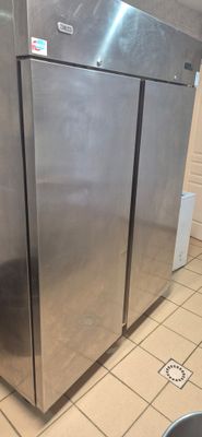 a stainless steel refrigerator in a kitchen with tile flooring
