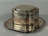 a silver plate with a silver lid and a silver tray on it