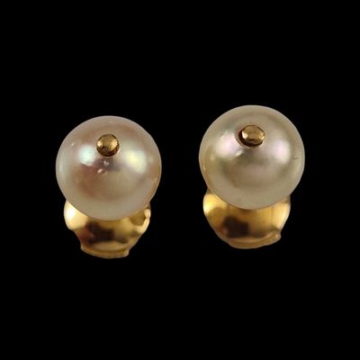 une paire de boucles d'oreilles en perles et en or sur fond noir