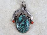 a close up of a silver and turquoise stone pendant on a white surface