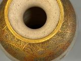 a vase with a gold decoration on it sitting on a table