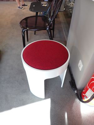 un tabouret blanc avec une assise rouge au milieu d'une pièce