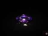 a purple diamond on a black surface in the dark