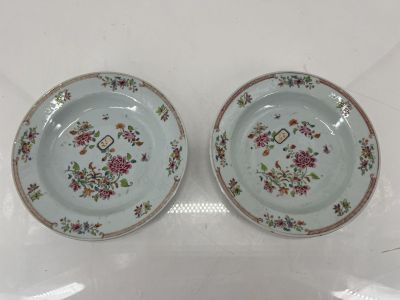 two plates with floral designs on them sitting on a table