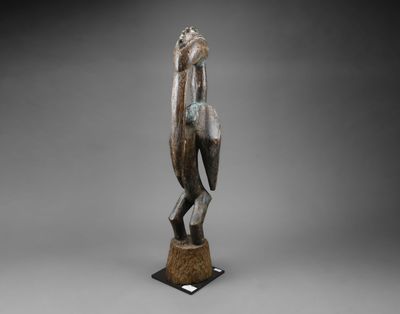 une statue en bronze d'une femme tenant un oiseau sur un piédestal