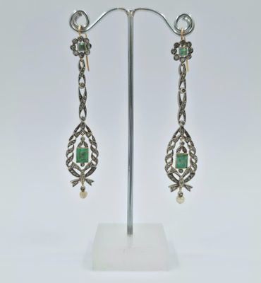 une paire de boucles d'oreilles en argent et émeraude, présentée sur un présentoir