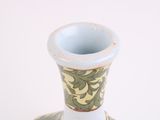 a white vase with a green and yellow design on it