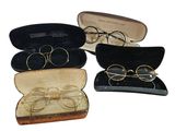 trois paires de lunettes se trouvent dans un étui posé sur une surface blanche