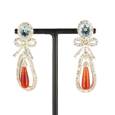une photo d'une paire de boucles d'oreilles ornées de pierres orange et bleues