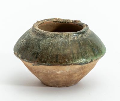 un vase vert et marron posé sur une surface blanche