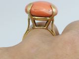 an image of a woman ' s hand holding a ring with an orange stone on it