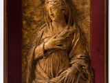 une sculpture en bois représentant une femme tenant un bébé dans ses bras, dans un cadre en bois