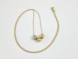 a close up of a gold necklace with two balls on a chain