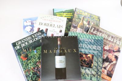 beaucoup de livres et une bouteille de vin sur la table