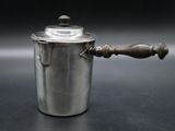 une casserole en argent avec une poignée en bois posée sur une table