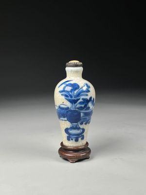 blue and white porcelain vase with a wooden stand on a gray surface