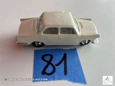 une petite voiture blanche suspendue à un ruban bleu, posée sur une table blanche