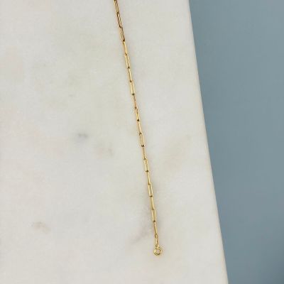 un collier en or avec une chaîne posé sur une dalle de marbre