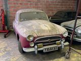 two old cars parked in a garage next to each other