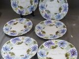 six assiettes bleues et blanches ornées de fleurs violettes, posées sur une table