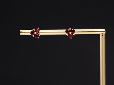 a pair of gold and ruby flower earrings on a black background
