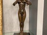 une statue en bronze représentant une femme debout sur une table en verre