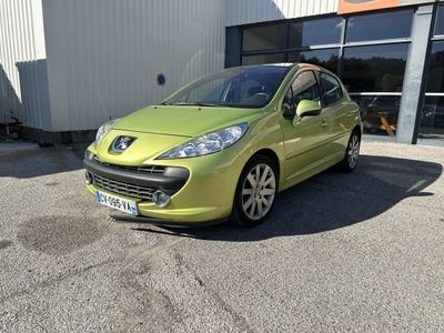 La voiture verte est garée devant un immeuble, sur un parking.