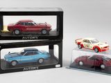 trois petites voitures sont exposées dans une vitrine posée sur une surface blanche