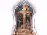 a bottle with a statue inside of it on a white surface