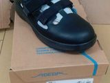 black leather school shoes with velcro straps on top of a cardboard box
