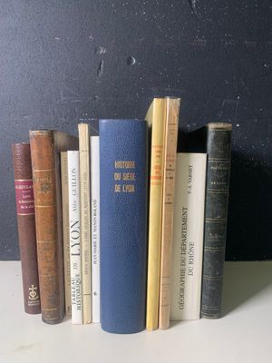 Plusieurs livres sont alignés sur une étagère devant un mur noir.
