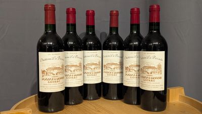 six bottles of red wine are lined up on a wooden barrel