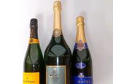 trois bouteilles de champagne sont alignées sur une surface blanche