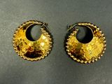 two pairs of gold earrings on a black surface