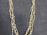 un collier composé de trois rangs de perles de verre sur fond gris