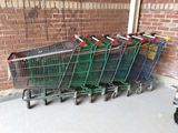 many shopping carts lined up against a brick wall
