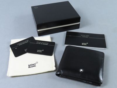 trois portefeuilles en cuir noir et un porte-cartes posés sur une table