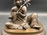bronze statue of a woman playing a musical instrument on a base
