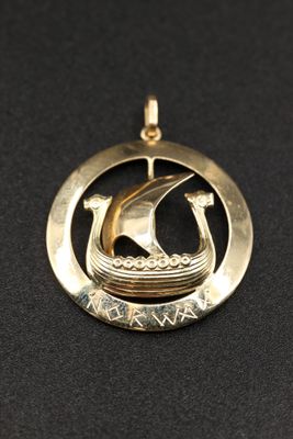 un pendentif en or avec un bateau au centre