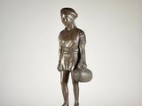 statue en bronze représentant un garçon tenant un ballon de basket, posée sur un socle en bois