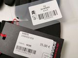 two pairs of black gloves with tags on them sitting on top of a table