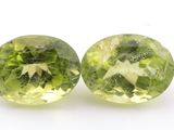 a pair of green and yellow gems on a white surface