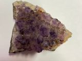 un améthorate violet sur une surface blanche, avec un petit morceau de roche au premier plan