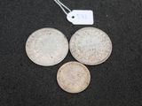 three silver coins and a tag on a black surface