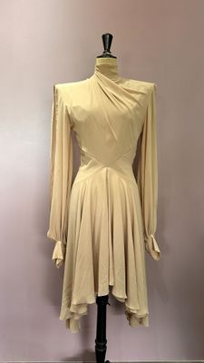 beige dress on a mannequin stand in front of a pink wall