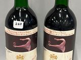 two bottles of red wine sitting next to each other on a table